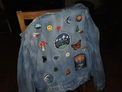 A denim jacket covered in pins, on a chair