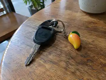 Scooter keys with a mango keyring on a table